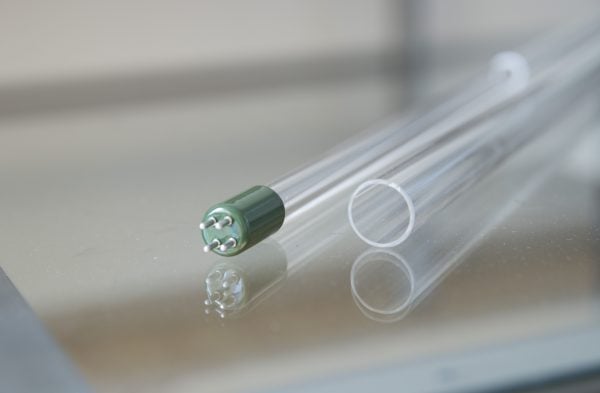 Precision medical syringe with a transparent barrel and green needle hub, placed on a reflective metallic surface, illustrating high-quality laboratory or medical device components.